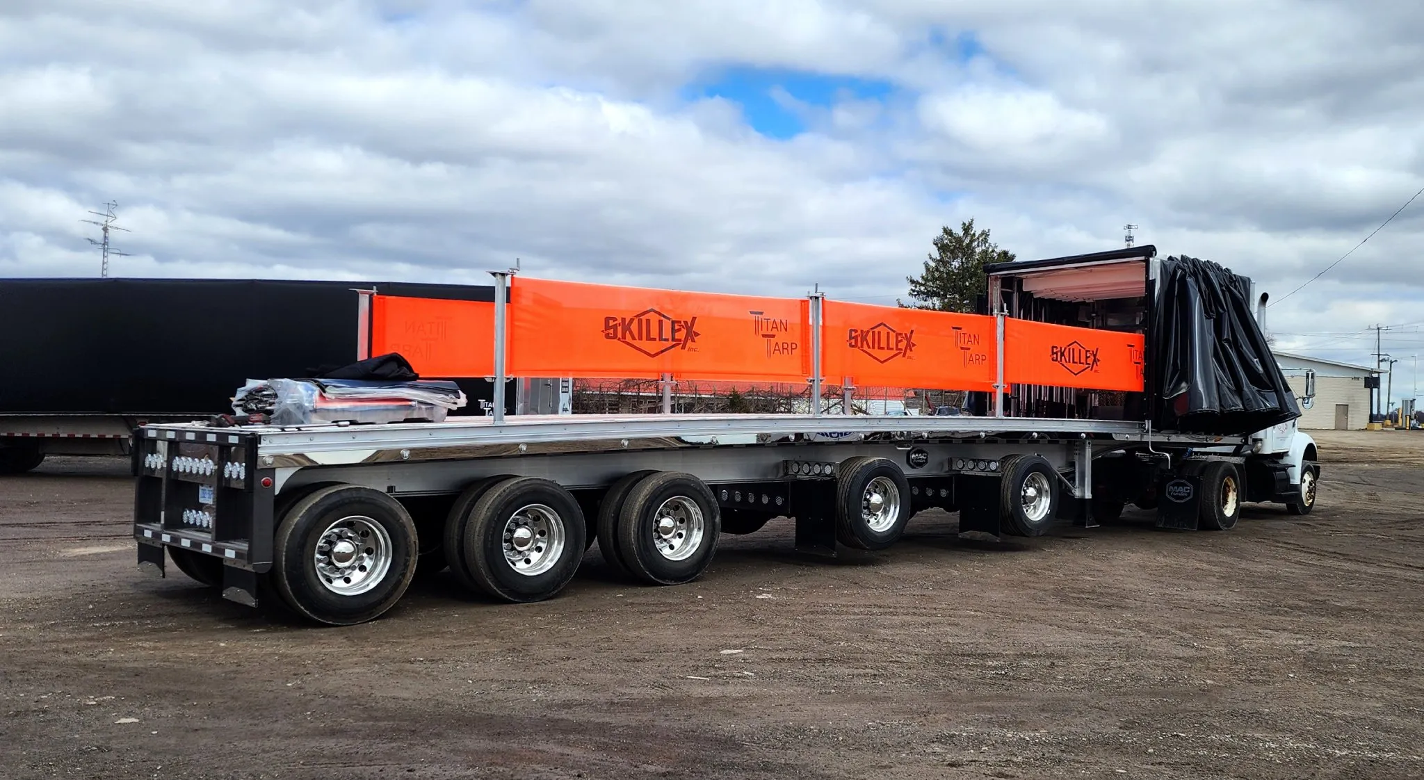 A fall prevention barrier along a flatbed deck, with the tarp system gathered at one end